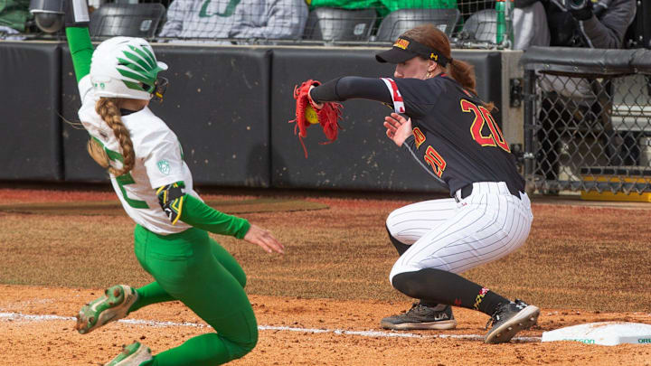 Oregon's Kai Luschar, left, tries to make it to third on an error throw ahead the tag by Maryland's Michaela Jones during the Jane Sanders Classic at Jane Sanders Stadium Saturday, March 2, 2024