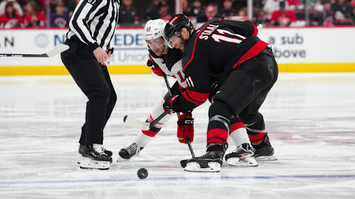 Apr 22, 2025; Raleigh, North Carolina, USA; New Jersey Devils center Nico Hischier (13) and Carolina Hurricanes center Jordan Staal (11) take a face off during the second period in game two of the first round of the 2025 Stanley Cup Playoffs at Lenovo Center. Mandatory Credit: James Guillory-Imagn Images