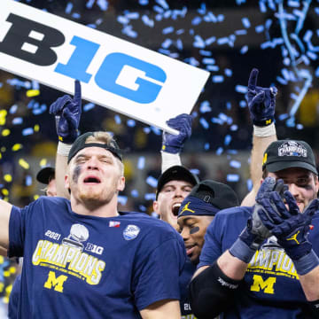 Dec 4, 2021; Indianapolis, IN, USA; Michigan Wolverines defensive end Aidan Hutchinson (97) lifts the Big Ten Championship Trophy after the game against the Iowa Hawkeyes  at Lucas Oil Stadium. Mandatory Credit: Trevor Ruszkowski-USA TODAY Sports