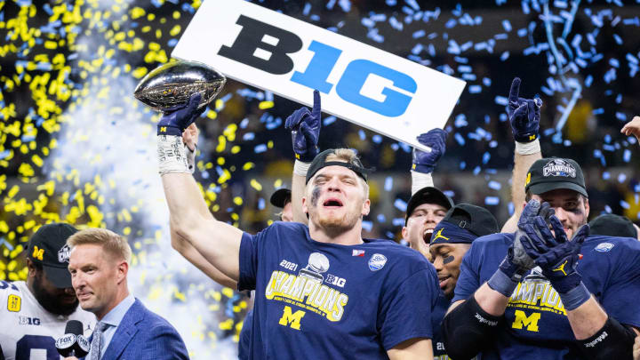 Dec 4, 2021; Indianapolis, IN, USA; Michigan Wolverines defensive end Aidan Hutchinson (97) lifts the Big Ten Championship Trophy after the game against the Iowa Hawkeyes  at Lucas Oil Stadium. Mandatory Credit: Trevor Ruszkowski-USA TODAY Sports