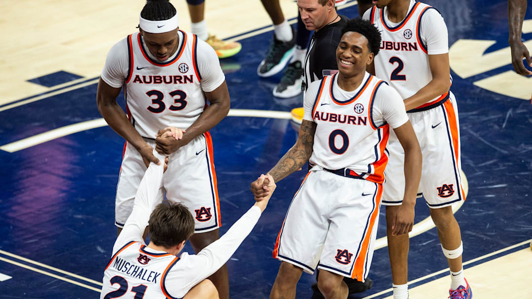 Auburn Tigers guard Blake Muschalek (21) is helped up from forward Sebastian Williams-Adams (33) and guard Tahaad Pettiford (0) as Auburn Tigers take on Jackson State Tigers at Neville Arena in Auburn, Ala. on Wednesday, Nov. 19, 2025. Auburn Tigers lead Jackson State Tigers 55-24 at halftime.