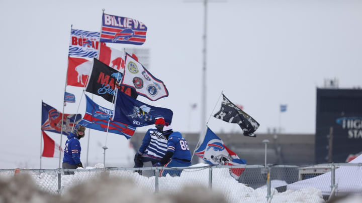 Jan 21, 2024; Orchard Park, New York, USA; Tailgaters climb a snow bank near flags in support of the Buffalo Bills before a 2024 AFC divisional round game between the Buffalo Bills and Kansas City Chiefs at Highmark Stadium. Mandatory Credit: Tina MacIntyre-Yee-USA TODAY Sports