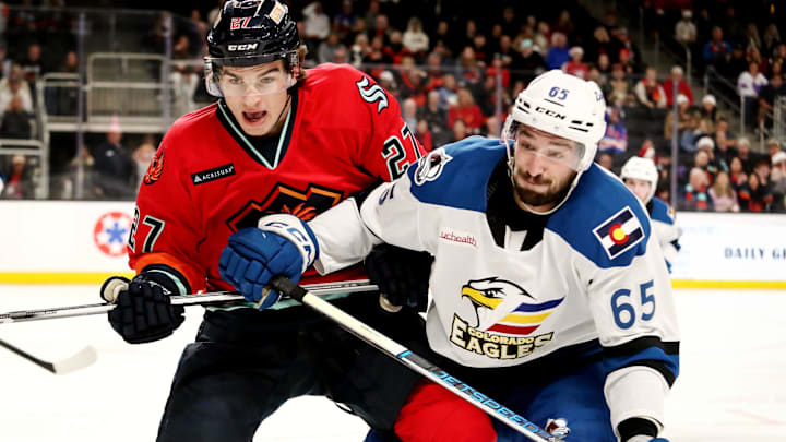 Coachella Valley Firebirds forward Ryan Winterton (27), left, and Colorado Eagles forward Cedric Pare (65) battle for the puck at Acrisure Arena in Palm Desert, Calif., on Sun., Dec. 17, 2023.