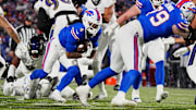 Buffalo Bills running back James Cook, carrying the ball, keeps low as teammate Buffalo Bills offensive tackle Spencer Brown blocks opening a spot for him during first half action at the Buffalo Bills divisional game against the Baltimore Ravens at Highmark Stadium in Orchard Park on Jan. 19, 2025.