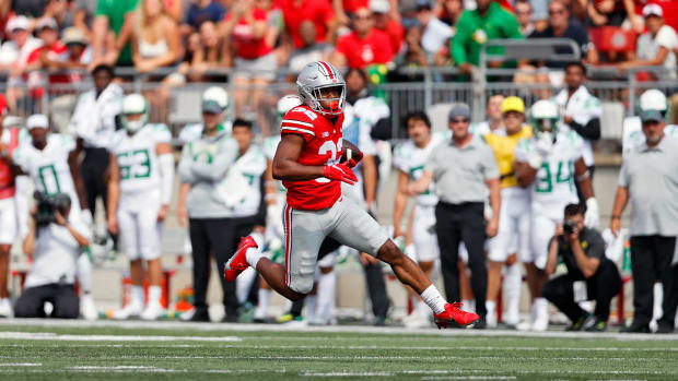 Running back runs with football in open field.