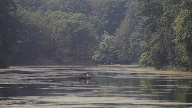 Two people in canoe in lake with trees in background