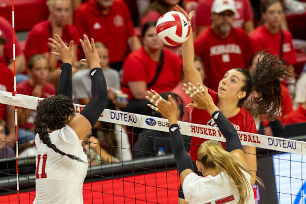 Nebraska opposite hitter Virginia Adriano goes up for a spike, while Teraya Sigler and Andi Jackson defend.