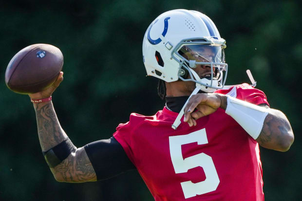 Football player Anthony Richardson throws a pass in training camp wearing a red jersey.