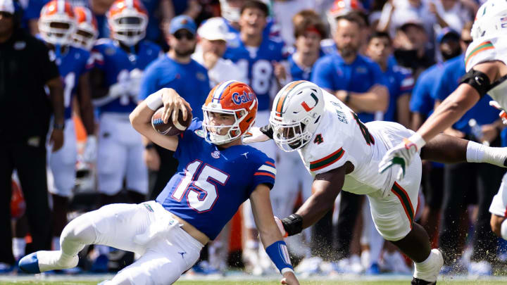 Aug 31, 2024; Gainesville, Florida, USA; Florida Gators quarterback Graham Mertz (15) slides for a first down while Miami Hurricanes defensive lineman Rueben Bain Jr. (4) attempts to tackle during the first half at Ben Hill Griffin Stadium. Mandatory Credit: Matt Pendleton-USA TODAY Sports