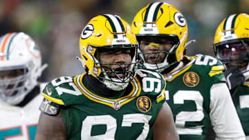 Green Bay Packers defensive tackle Kenny Clark (97) celebrates sacking Dolphins quarterback Tua Tagovailoa with Rashan Gary.