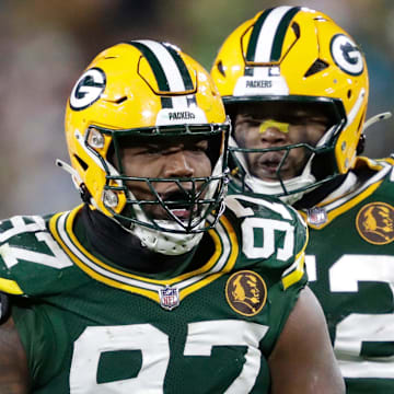 Green Bay Packers defensive tackle Kenny Clark (97) celebrates sacking Dolphins quarterback Tua Tagovailoa with Rashan Gary.