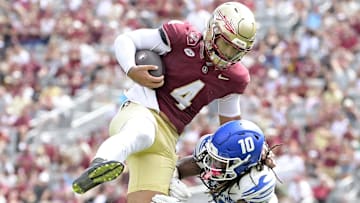 Sep 14, 2024; Tallahassee, Florida, USA; Florida State Seminoles quarterback DJ Uiagalelei (4) leaps against Memphis Tigers defensive back AJ Watts (10) and defensive back Greg Rubin (24) during the second half at Doak S. Campbell Stadium. Mandatory Credit: Melina Myers-Imagn Images