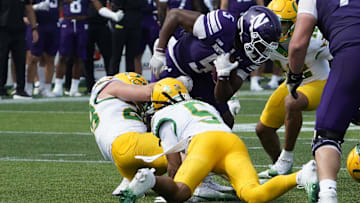 Sep 13, 2025; Evanston, Illinois, USA; Oregon Ducks defensive back Theran Johnson (5) tackles Northwestern Wildcats running back Caleb Komolafe (5) during the second half at Northwestern Medicine Field at Martin Stadium. Mandatory Credit: David Banks-Imagn Images