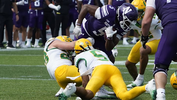 Sep 13, 2025; Evanston, Illinois, USA; Oregon Ducks defensive back Theran Johnson (5) tackles Northwestern Wildcats running back Caleb Komolafe (5) during the second half at Northwestern Medicine Field at Martin Stadium. Mandatory Credit: David Banks-Imagn Images