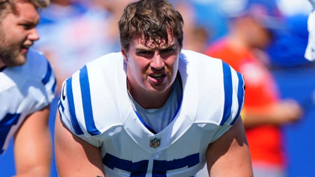 Colts guard Will Fries (white jersey with blue lines) talks to a teammate before a game. 