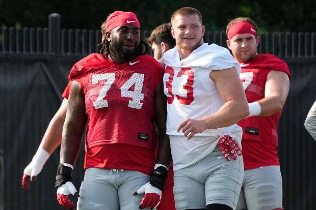 Offensive lineman and defensive lineman stretch together during practice.