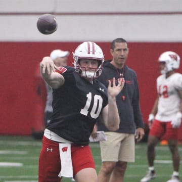 Wisconsin quarterback Tyler Van Dyke throws a pass as coach Luke Fickell watches during spring practice at the McClain Center in Madison, Wisconsin on Tuesday April 2, 2024.