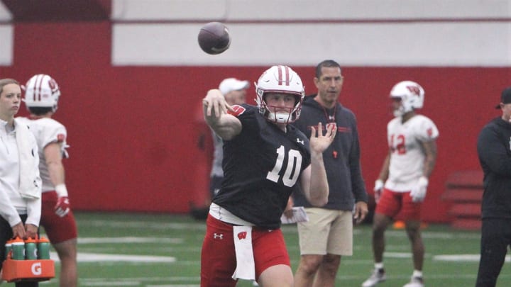 Wisconsin quarterback Tyler Van Dyke throws a pass as coach Luke Fickell watches during spring practice at the McClain Center in Madison, Wisconsin on Tuesday April 2, 2024.