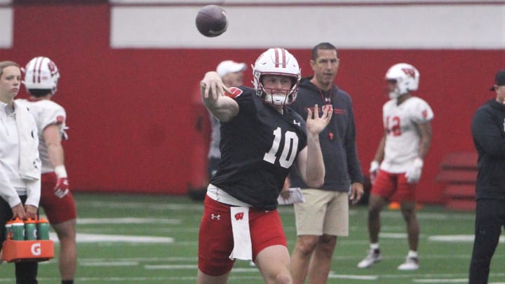 Wisconsin quarterback Tyler Van Dyke throws a pass as coach Luke Fickell watches during spring practice at the McClain Center in Madison, Wis.,on Tuesday, April 2, 2024.