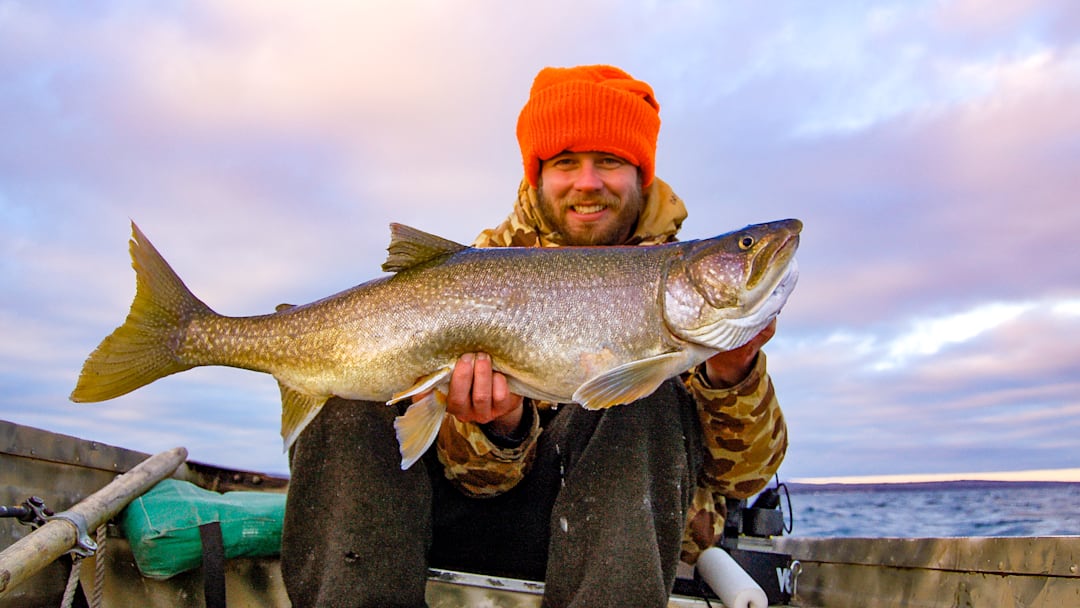 The author holds a 14-pound Lake Superior lake trout caught while jigging from a small boat on a rare warm, calm January day—proof that winter sometimes rewards dedication.