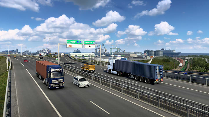 A Eruopean highway with turcks and cars dirivng along either side with a city in the background.