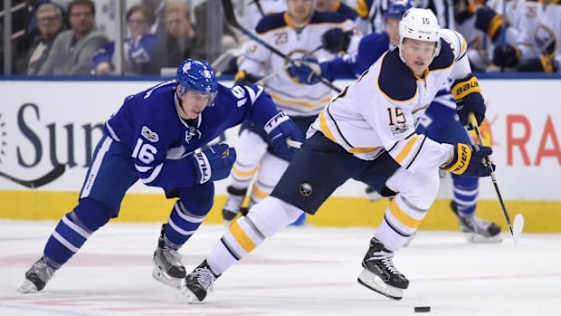Hockey players skate toward puck
