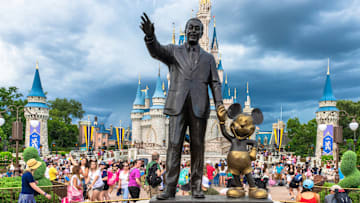 ORLANDO, FLORIDA, UNITED STATES – 2019/07/17: Walt Disney and Mickey Mouse statue inside of the Magic Kingdom theme park . The Cinderella castle can b