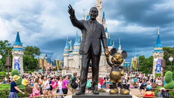 ORLANDO, FLORIDA, UNITED STATES – 2019/07/17: Walt Disney and Mickey Mouse statue inside of the Magic Kingdom theme park . The Cinderella castle can b
