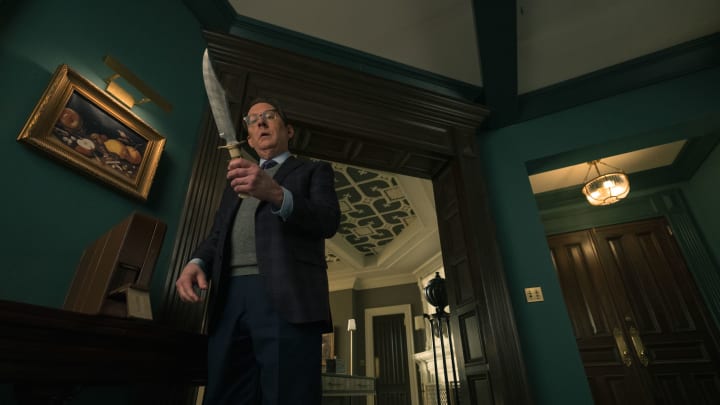 Leland Townsend (Michael Emerson) stands in his apartment holding a large knife