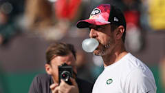 New York Jets quarterback Aaron Rodgers blowing a bubble with gum on the sidelines. 