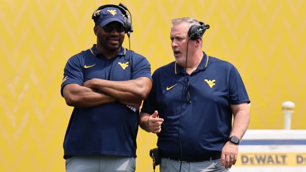 West Virginia University defensive line coach AJ Jackson (left) chats with offensive line coach Matt Moore (right) during the 2024 Gold-Blue Spring Game.