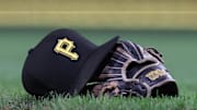Sep 16, 2025; Pittsburgh, Pennsylvania, USA; A hat and glove belonging to Pittsburgh Pirates third baseman Jared Triolo (not pictured) on the field against the Chicago Cubs during the sixth inning at PNC Park. Mandatory Credit: Charles LeClaire-Imagn Images