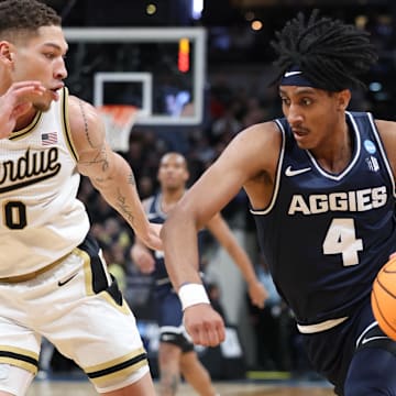 Mar 24, 2024; Indianapolis, IN, USA; Utah State Aggies guard Ian Martinez (4) dribbles against Purdue Boilermakers forward Mason Gillis (0) during the first half at Gainbridge FieldHouse. Mandatory Credit: Trevor Ruszkowski-Imagn Images