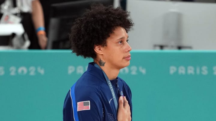 Aug 11, 2024; Paris, France;  United States center Brittney Griner (15) listens to the national anthem on the podium after defeating France in the women’s basketball gold medal game during the Paris 2024 Olympic Summer Games at Accor Arena. 