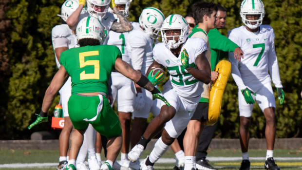 Oregon wide receiver Jurrion Dickey attempts to dodge a tackle from defensive back Kobe Savage during practice with the Orego