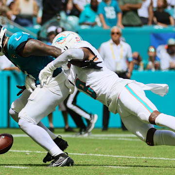 Sep 8, 2024; Miami Gardens, Florida, USA; Jacksonville Jaguars running back Travis Etienne Jr. (1) fumbles the football after a tackle from Miami Dolphins safety Jevon Holland (8) during the third quarter at Hard Rock Stadium. Mandatory Credit: Sam Navarro-Imagn Images