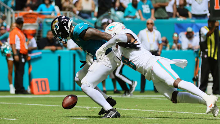 Sep 8, 2024; Miami Gardens, Florida, USA; Jacksonville Jaguars running back Travis Etienne Jr. (1) fumbles the football after a tackle from Miami Dolphins safety Jevon Holland (8) during the third quarter at Hard Rock Stadium. Mandatory Credit: Sam Navarro-Imagn Images