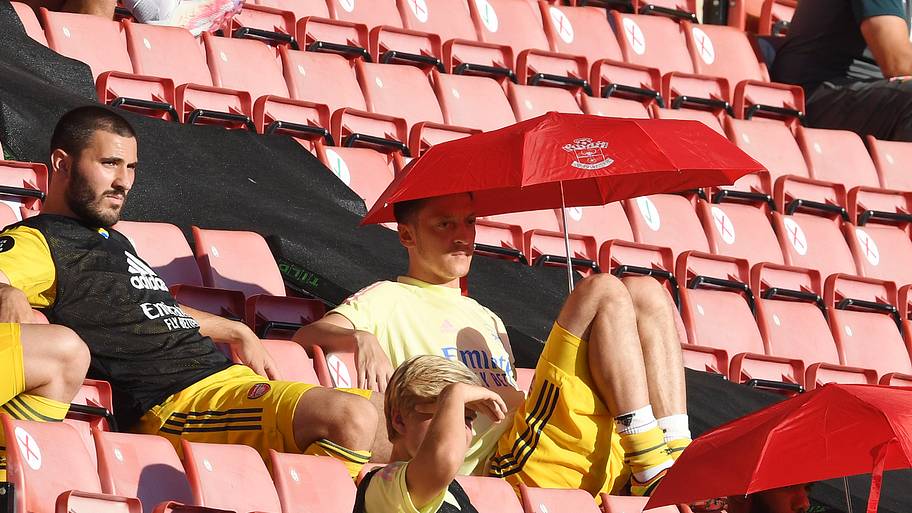 Mesut Özil hiding under an umbrella.