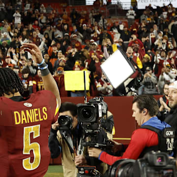 Washington Commanders quarterback Jayden Daniels celebrates while leaving the field.