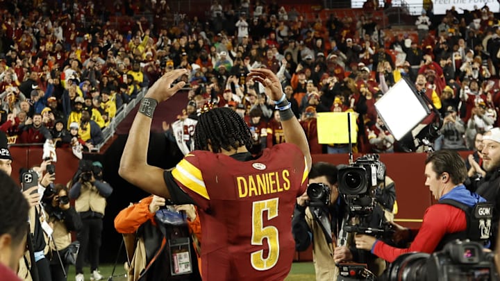 Washington Commanders quarterback Jayden Daniels celebrates while leaving the field.