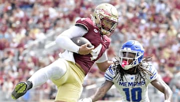 Sep 14, 2024; Tallahassee, Florida, USA; Florida State Seminoles quarterback DJ Uiagalelei (4) leaps against Memphis Tigers defensive back AJ Watts (10) and defensive back Greg Rubin (24) during the second half at Doak S. Campbell Stadium. Mandatory Credit: Melina Myers-Imagn Images