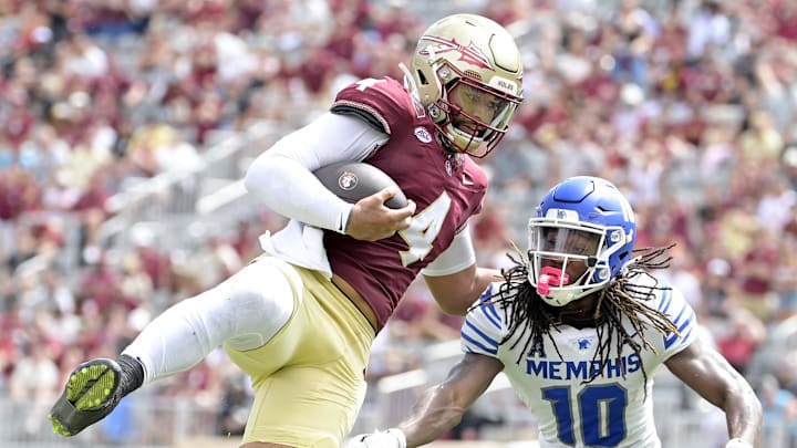 Sep 14, 2024; Tallahassee, Florida, USA; Florida State Seminoles quarterback DJ Uiagalelei (4) leaps against Memphis Tigers defensive back AJ Watts (10) and defensive back Greg Rubin (24) during the second half at Doak S. Campbell Stadium. Mandatory Credit: Melina Myers-Imagn Images