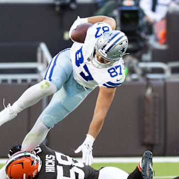 Sep 8, 2024; Cleveland, Ohio, USA; Dallas Cowboys tight end Jake Ferguson (87) falls over Cleveland Browns linebacker Jordan Hicks (58) as he is tackled around his ankle during the third quarter at Huntington Bank Field. 