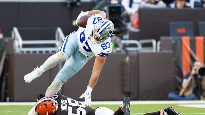 Sep 8, 2024; Cleveland, Ohio, USA; Dallas Cowboys tight end Jake Ferguson (87) falls over Cleveland Browns linebacker Jordan Hicks (58) as he is tackled around his ankle during the third quarter at Huntington Bank Field. 