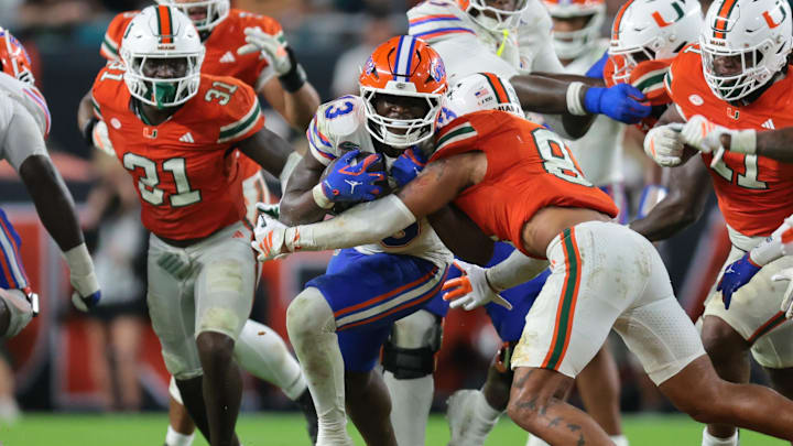 Sep 20, 2025; Miami Gardens, Florida, USA; Florida Gators running back Jadan Baugh (13) carries the football against Miami Hurricanes defensive back Jakobe Thomas (8) during the third quarter at Hard Rock Stadium. Mandatory Credit: Sam Navarro-Imagn Images