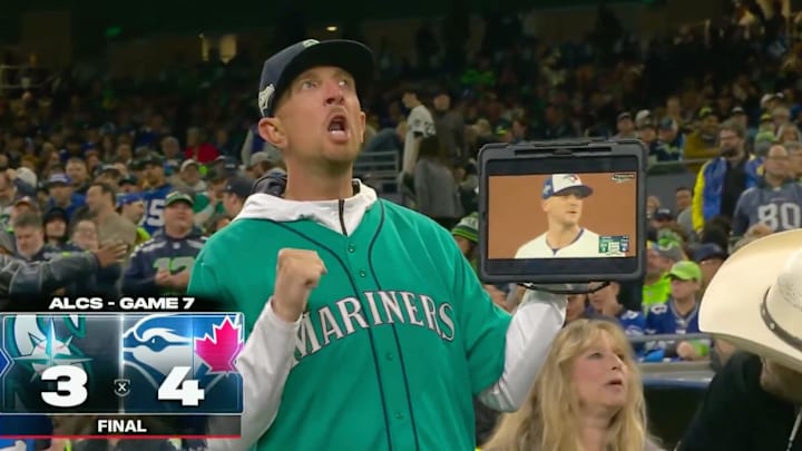 A Mariners fans cheers on his team while ESPN reveals the game is already over and they lost. A Mariners fans cheers on his team while ESPN reveals the game is already over and they lost.