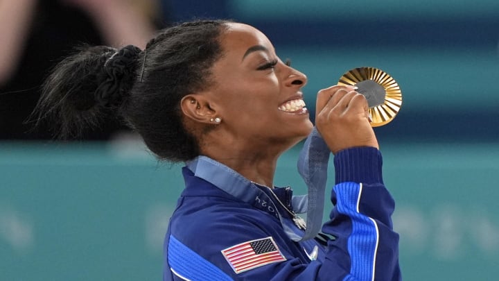 Aug 1, 2024; Paris, France; Simone Biles of the United States celebrates her gold medal in the womenís gymnastics all-around during the Paris 2024 Olympic Summer Games at Bercy Arena.