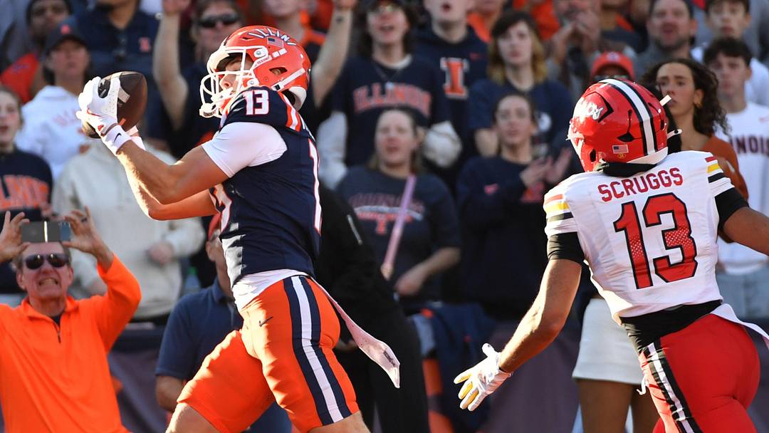 Nov 15, 2025; Champaign, Illinois, USA; Illinois Fighting Illini wide receiver Hudson Clement (13) catches a touchdown pass as Maryland Terrapins defensive back Lavain Scruggs (13) pursues during the first half at Memorial Stadium. Mandatory Credit: Ron Johnson-Imagn Images