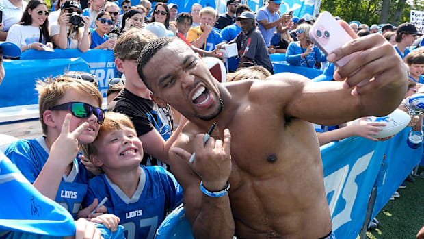 Detroit Lions wide receiver Amon-Ra St. Brown uses someones iPhone to do a selfie with kids after practic