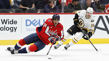 Oct 2, 2025; Washington, District of Columbia, USA; Washington Capitals right wing Justin Sourdif (34) loses an edge while skating with the puck as Boston Bruins center John Beecher (19) chases in the second period at Capital One Arena. Mandatory Credit: Geoff Burke-Imagn Images